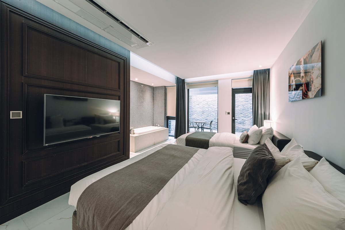 Quarto de hotel com televisão grande, banheira e varanda com vista para a água.