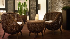 Wicker chairs with cushions, a round table, and a candle on a wooden deck. - The Classic by Hotelone (Wanju)