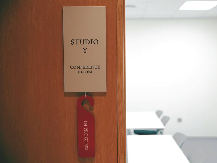 A door with a sign reading "STUDIO Y CONFERENCE ROOM" and a red tag hanging from it.