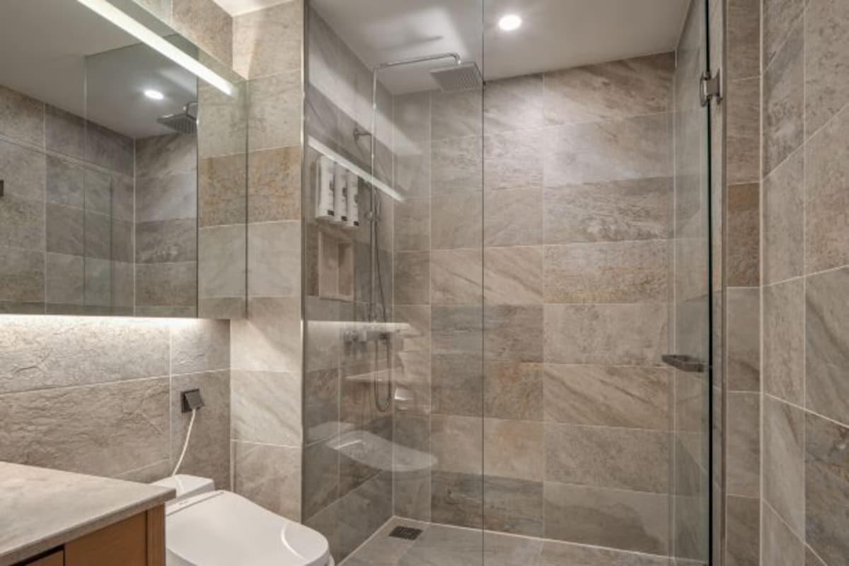 Un baño moderno con ducha de vidrio, inodoro y tocador con espejo.