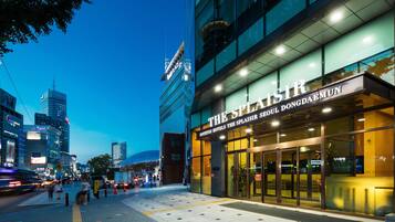 A hotel with a modern facade, large glass windows, and a prominent sign.