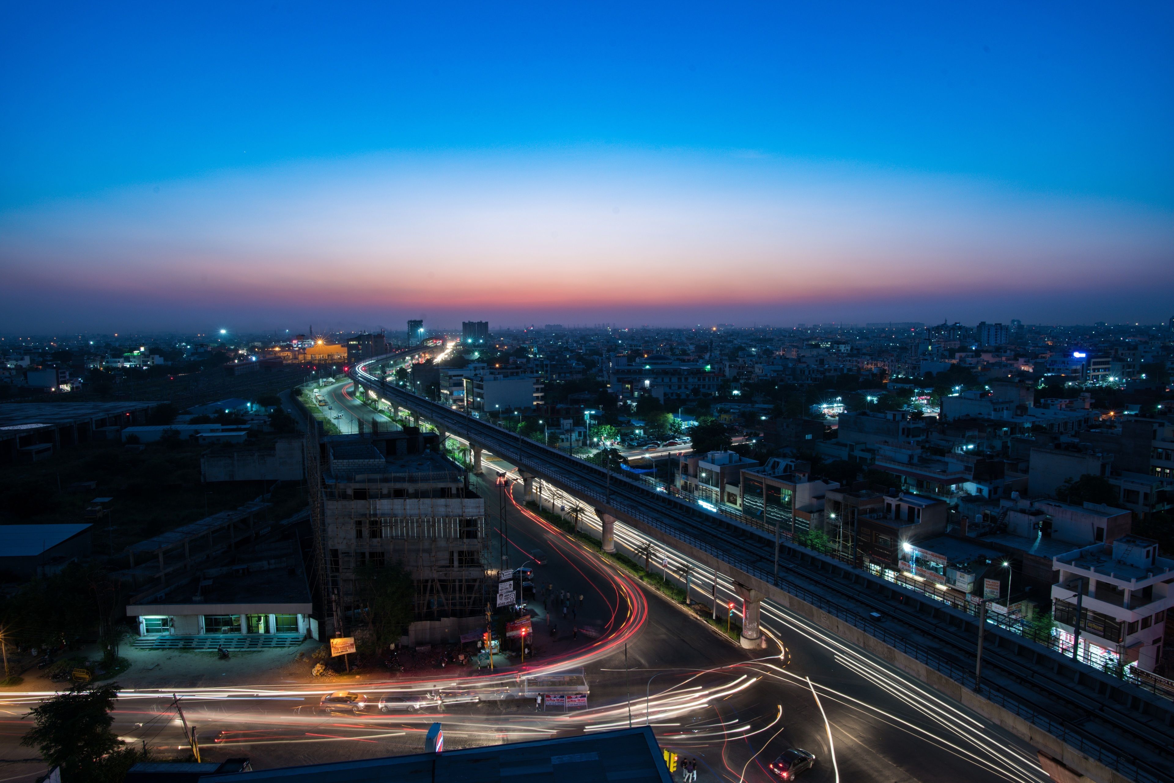 A cityscape at dusk with a highway and overpass, buildings, and streetlights.