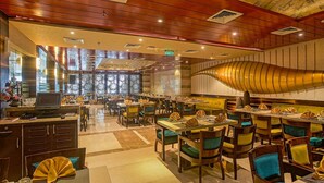 A restaurant with multiple dining tables and chairs, a reception desk, and a large decorative wall. - Renest Jaipur (Jaipur)