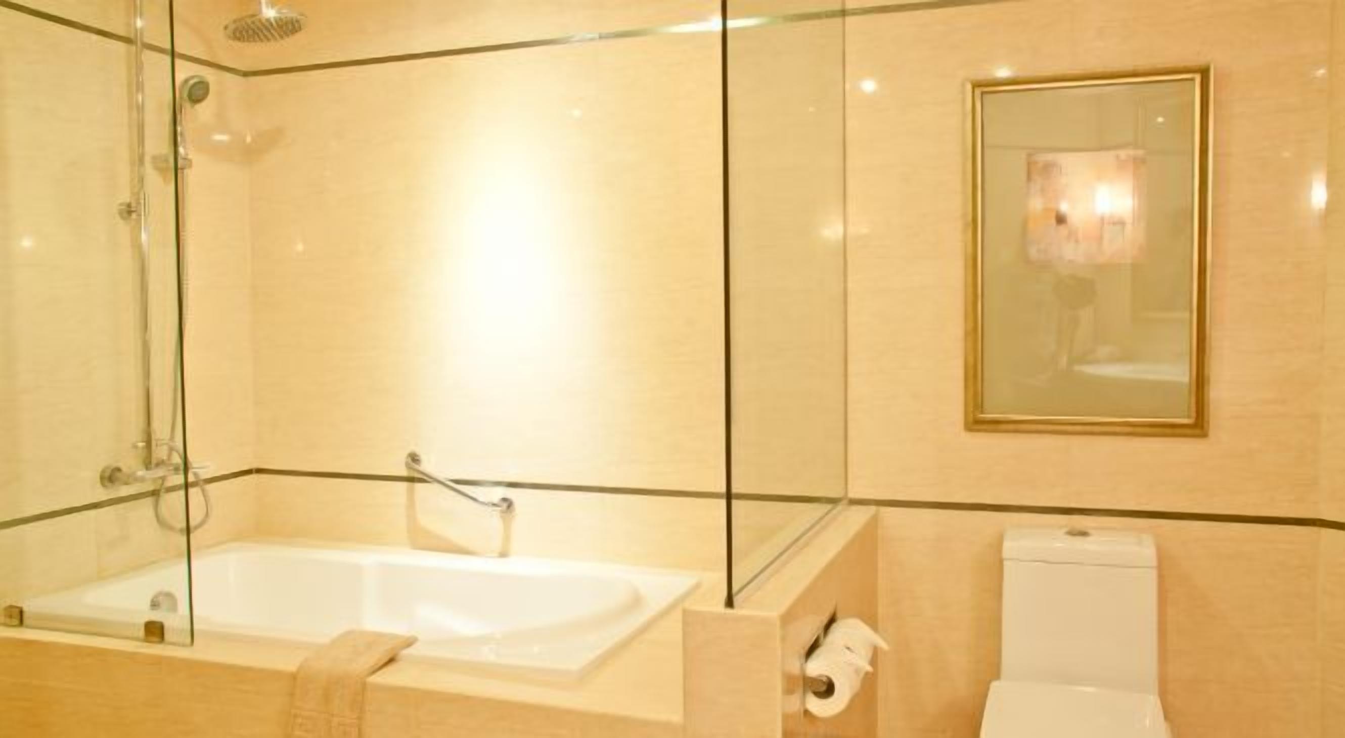 A modern bathroom with a glass-enclosed shower, a standalone bathtub, and a toilet.