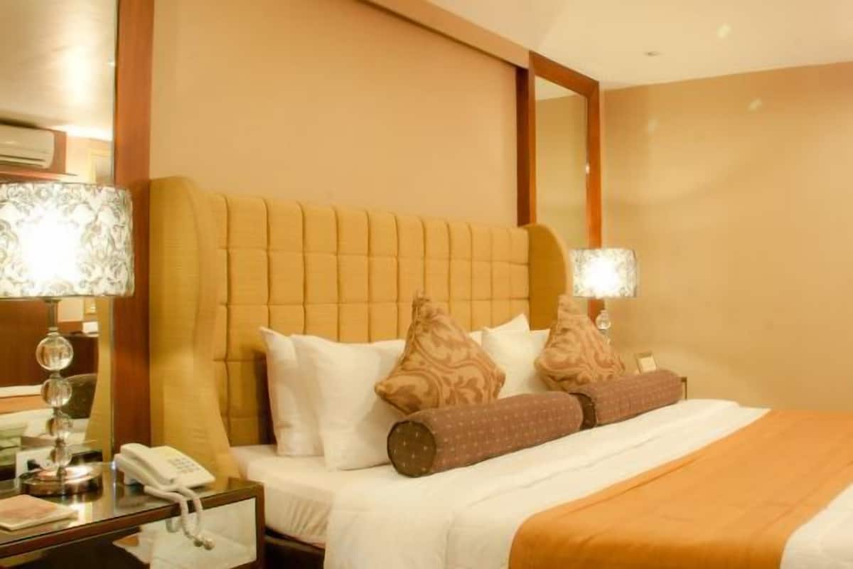 A hotel room with a large bed, a bedside table with a lamp, and a telephone.