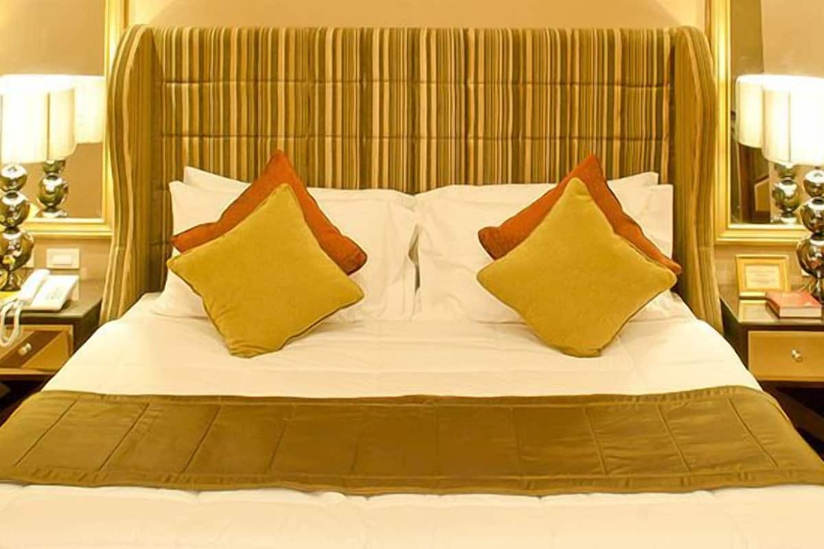 A hotel room with a large bed, two bedside tables, lamps, and a mirror.