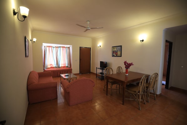Un salon comprenant un canapé, une table à manger avec des chaises, un ventilateur de plafond et un téléviseur.