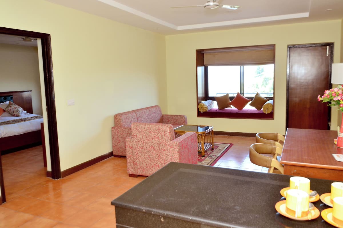 A room with a bed, a sofa, a dining table, and a small table with cups.