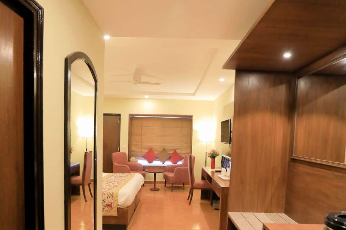 A hotel room with a bed, a desk, a chair, a TV, and a mirror.