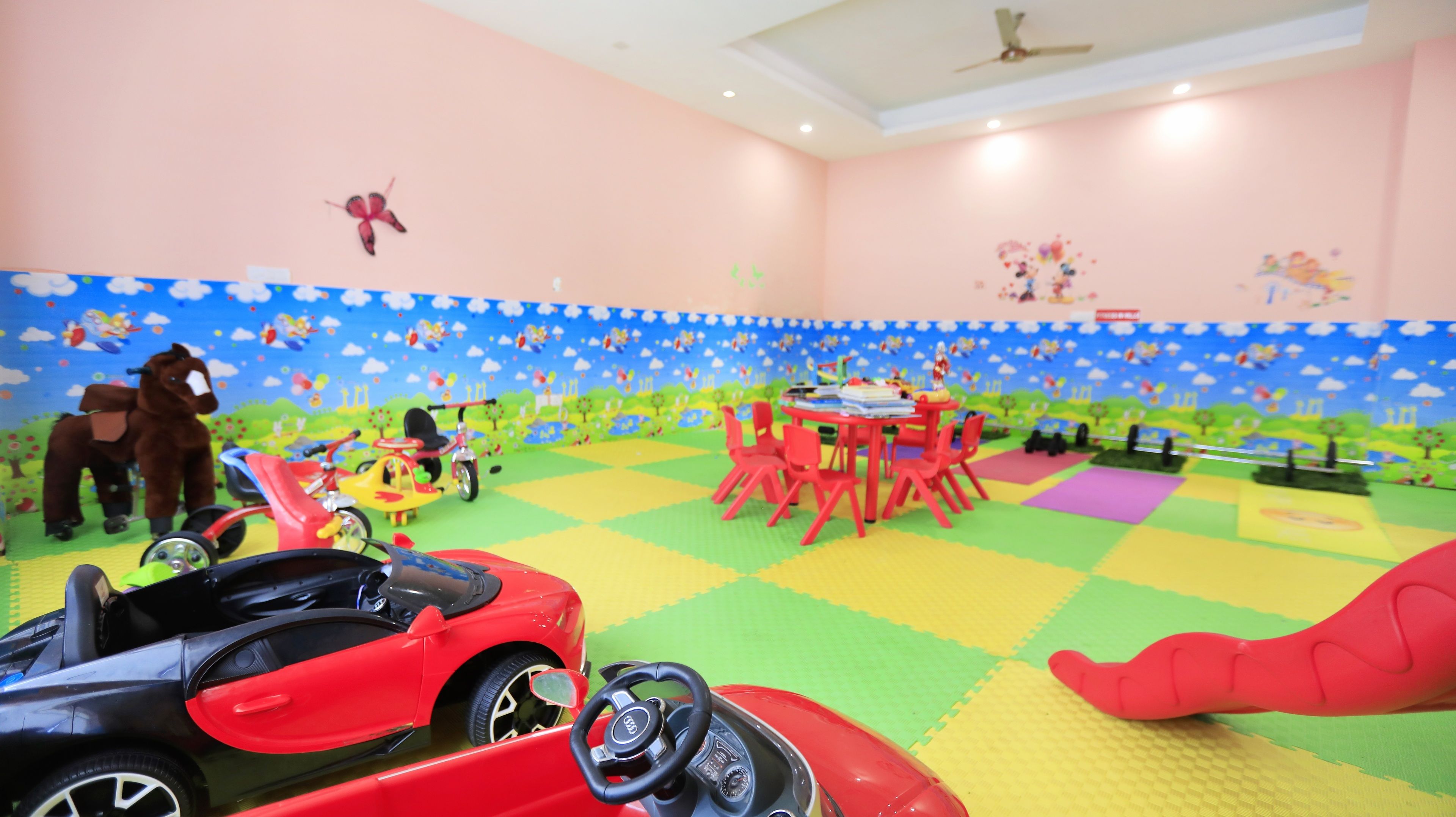Une salle de jeux avec des tapis colorés, des voitures miniatures et une figurine de cheval.