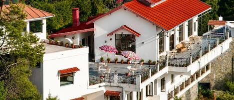 Un edificio de varios pisos con techo rojo, balcones y terrazas al aire libre.