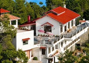 A multi-story building with a red roof, balconies, and outdoor seating areas. - ECKO Woodsvilla Resort (Ranikhet)