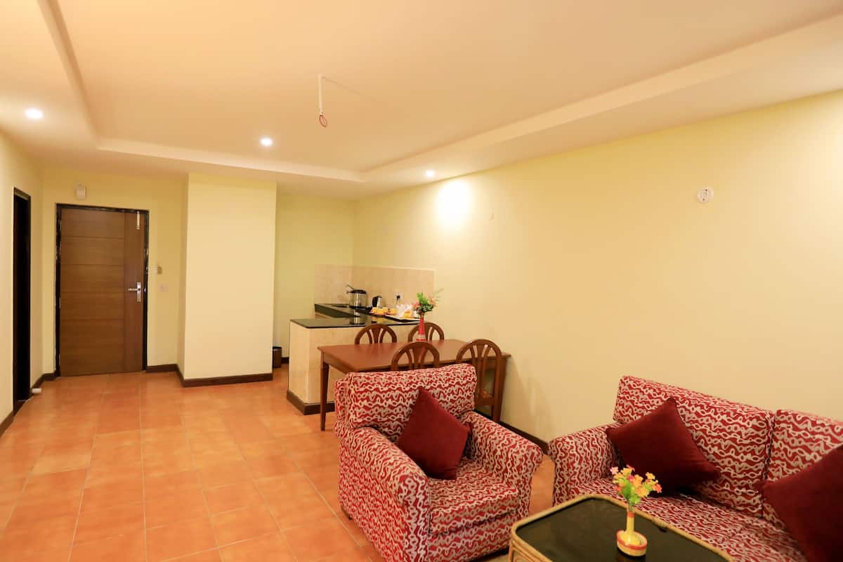 A living room with a sofa, armchair, and coffee table, a dining area with chairs and a table, and a kitchen with a stove and sink.