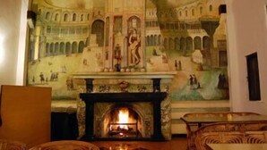 A room with a fireplace, a mural on the wall, and wicker furniture. - ECKO Woodsvilla Resort (Ranikhet)