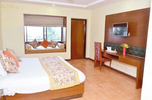 Habitación de hotel con cama, escritorio, televisión y ventana con vistas.
