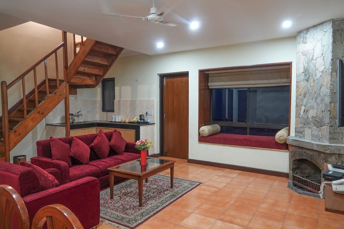 A living room with a red sofa, wooden coffee table, and a stone fireplace.