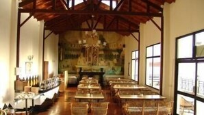 A long dining area with high ceilings and large windows, featuring wicker chairs and tables. - ECKO Woodsvilla Resort (Ranikhet)