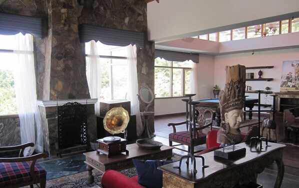 A spacious room with a stone fireplace, a pool table, and a billiards table.