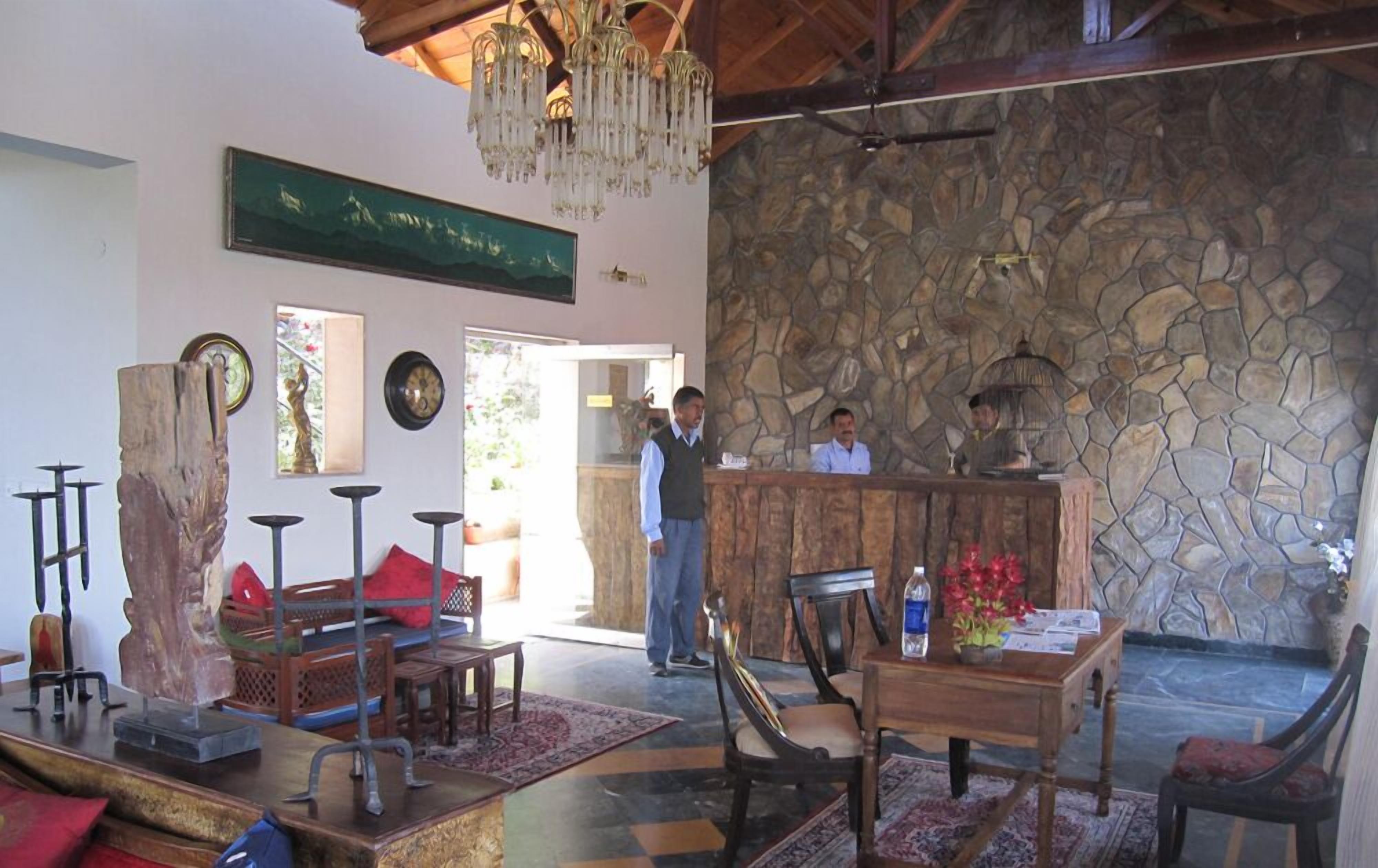 Un vestíbulo con pared de piedra, muebles de madera, una recepción y una araña.