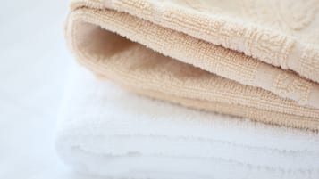 A folded beige towel on top of a white towel.