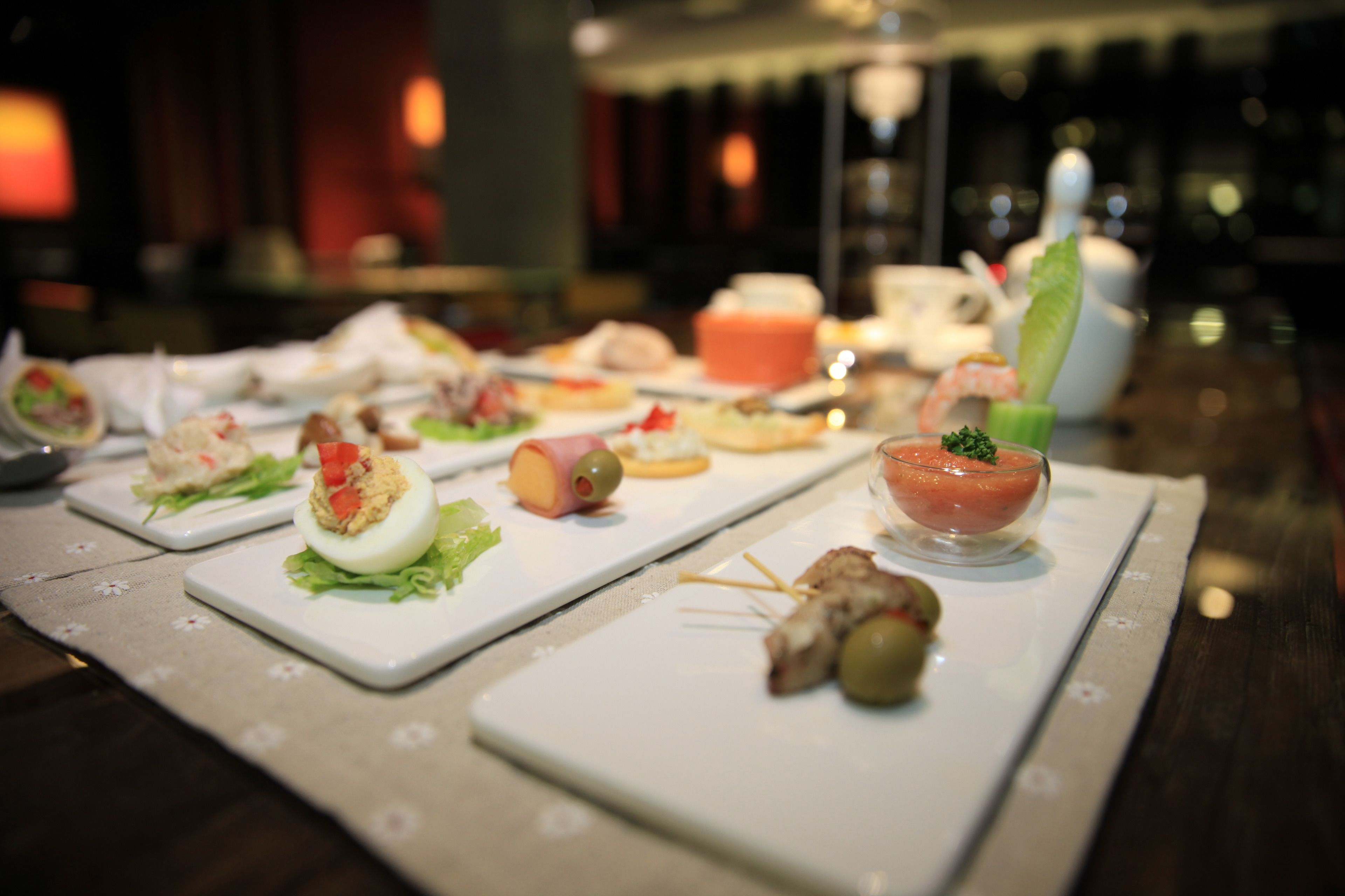 Une table sur laquelle sont disposés divers amuse-gueules et un cocktail, le tout sur une nappe à motifs floraux.