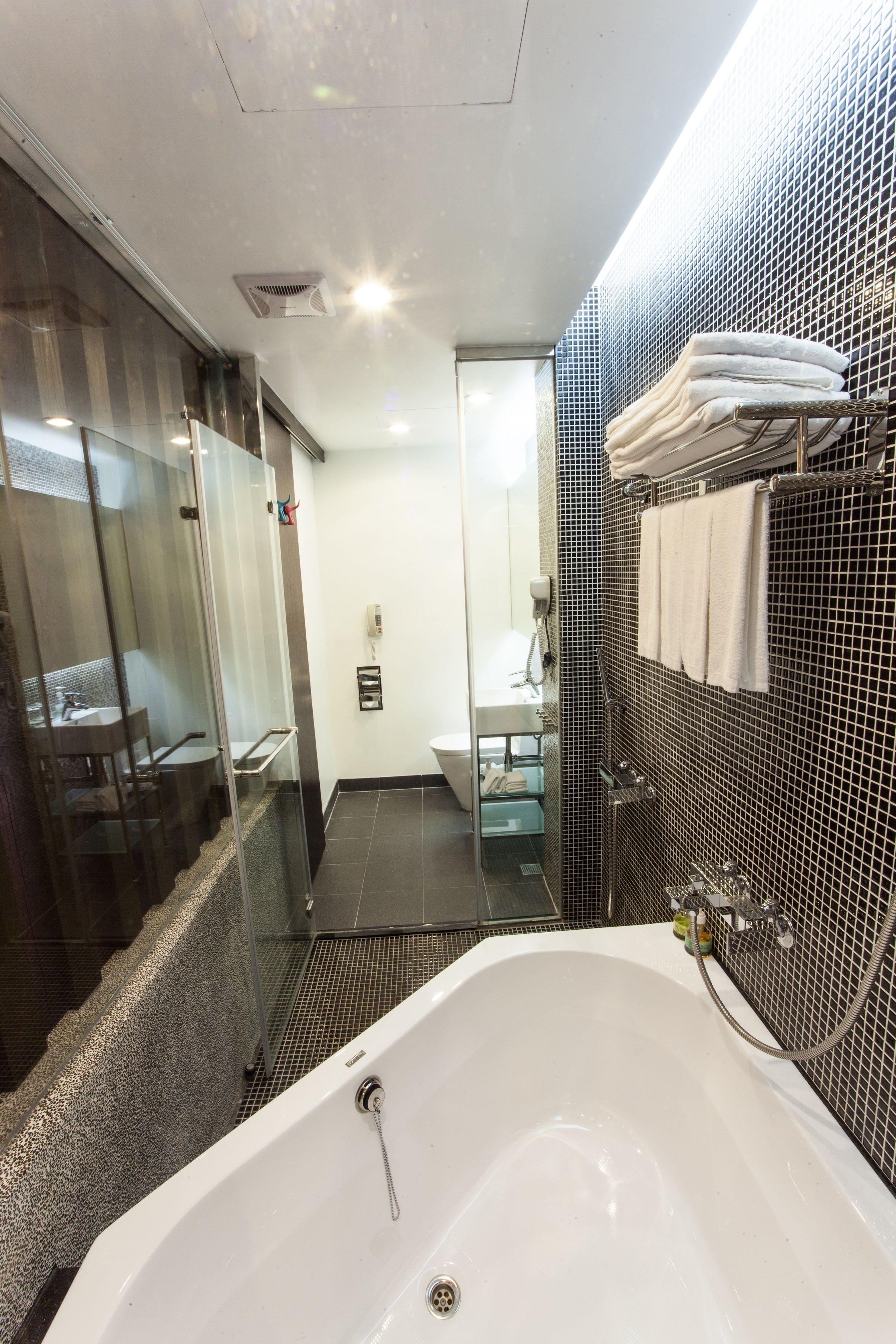 A modern bathroom with a large bathtub, a glass shower enclosure, and a sink with a mirror.
