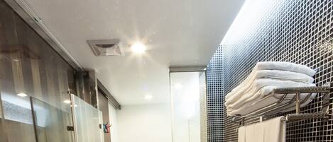 A modern bathroom with a large bathtub, a glass shower enclosure, and a sink with a mirror.