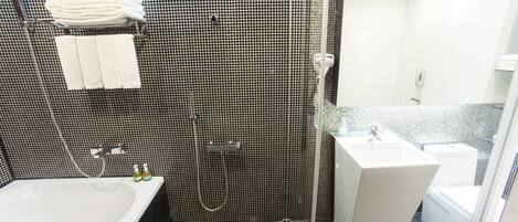Un baño moderno con pared de azulejos blanco y negro, un lavabo blanco, zona de ducha y un inodoro.