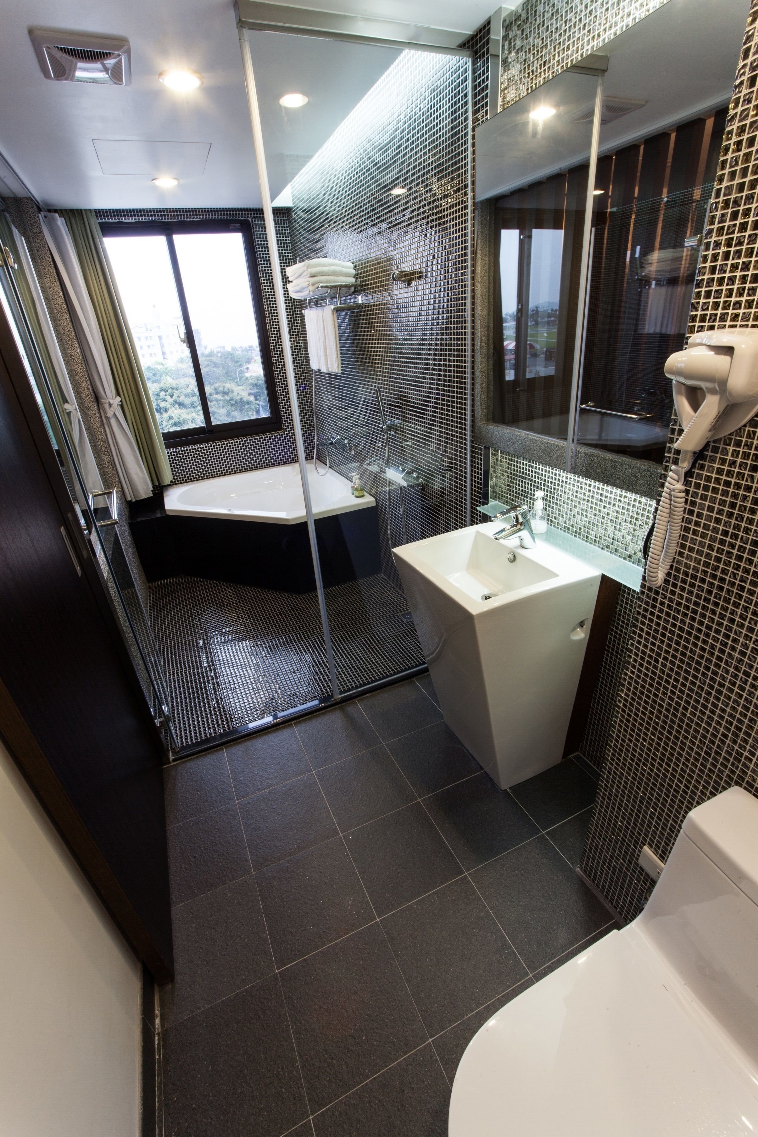 A modern bathroom with a glass-enclosed shower, a white sink, and a large mirror.