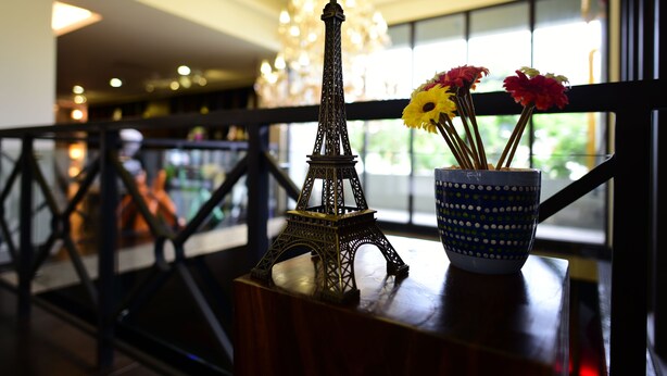 Una reproducción de la Torre Eiffel sobre una mesa con un florero de lunares que contiene flores.