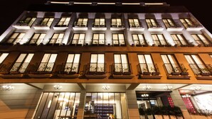 Un hotel de varios pisos con balcones iluminados y una entrada imponente.