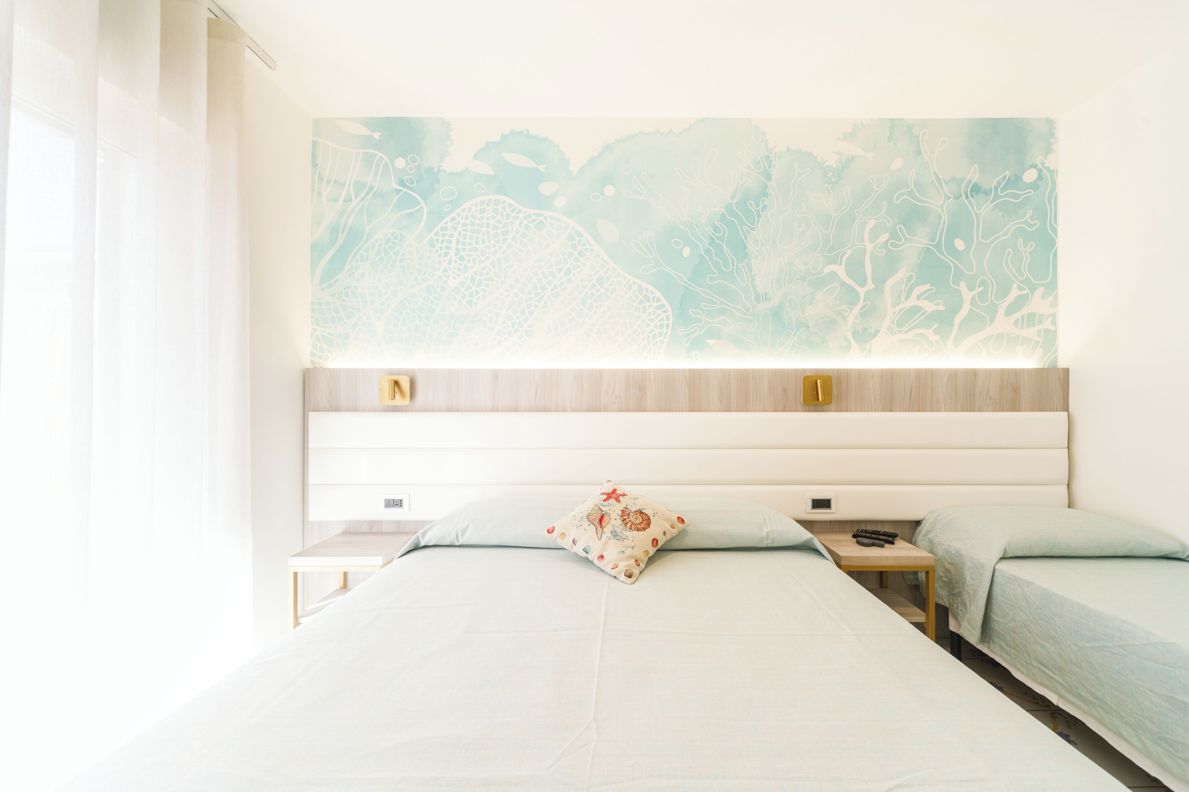 A hotel room with a large bed, two bedside tables, a nightstand, and a wall-mounted artwork.