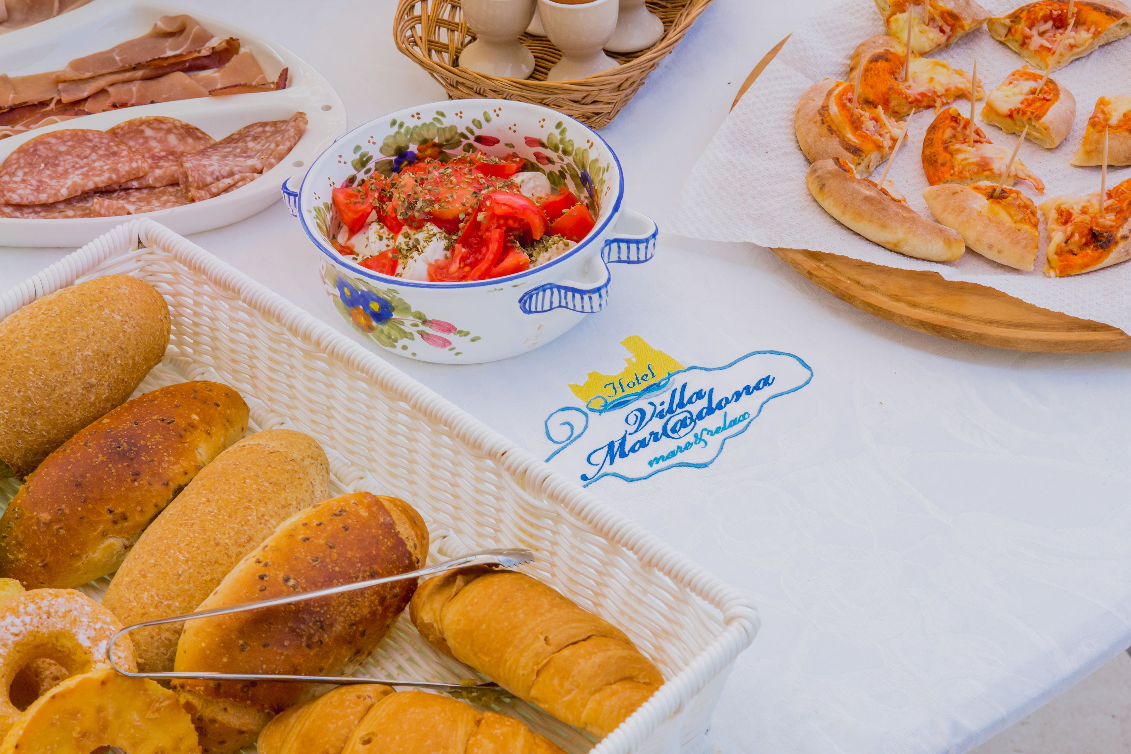 A table with various food items including bread, a bowl of salad, and sliced pizza.