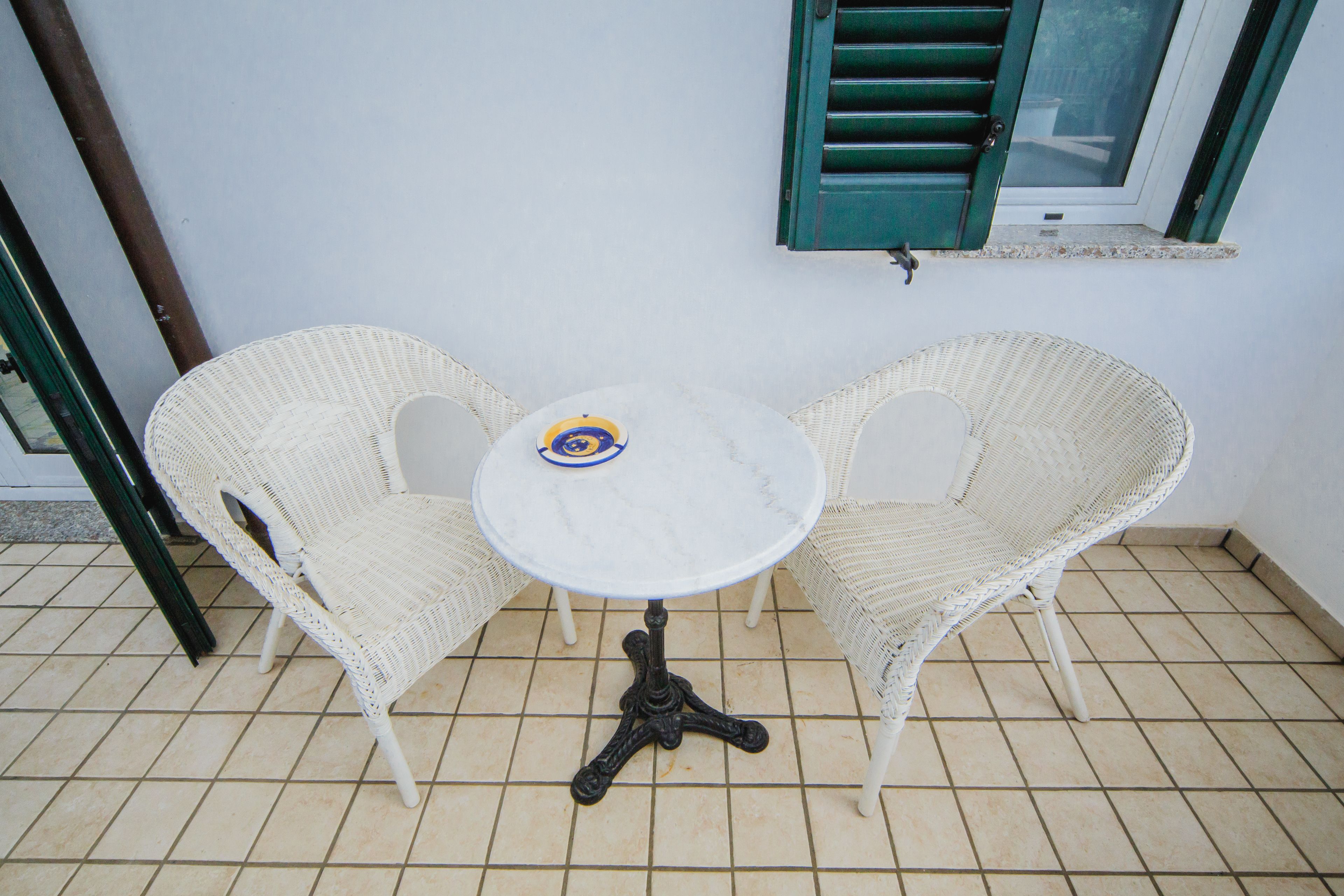 Ein kleiner Sitzbereich im Freien mit zwei Korbstühlen und einem runden Tisch.