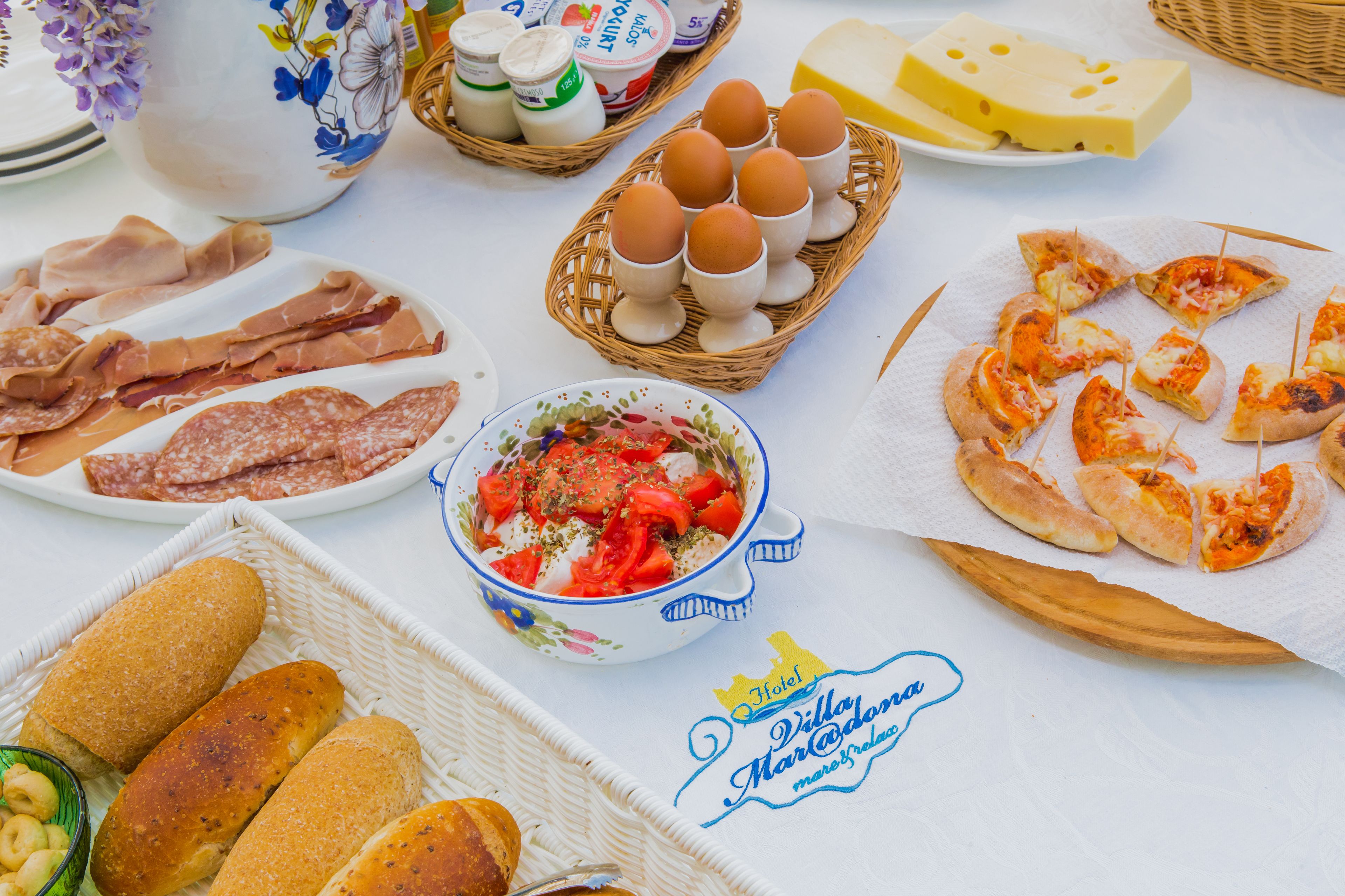 A table with various food items including bread, cheese, eggs, and a bowl of salad.