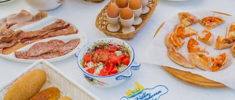 A table with various food items including bread, cheese, eggs, and a bowl of salad.