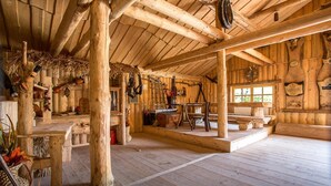 A rustic wooden interior with exposed beams, a wooden table, and a window with a view.