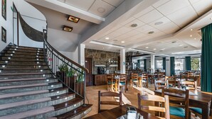 A spacious restaurant with a curved staircase, wooden tables, and chairs.