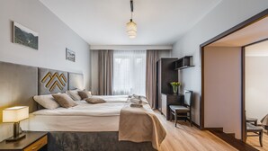 A modern hotel room with a large bed, a desk, a chair, and a TV.