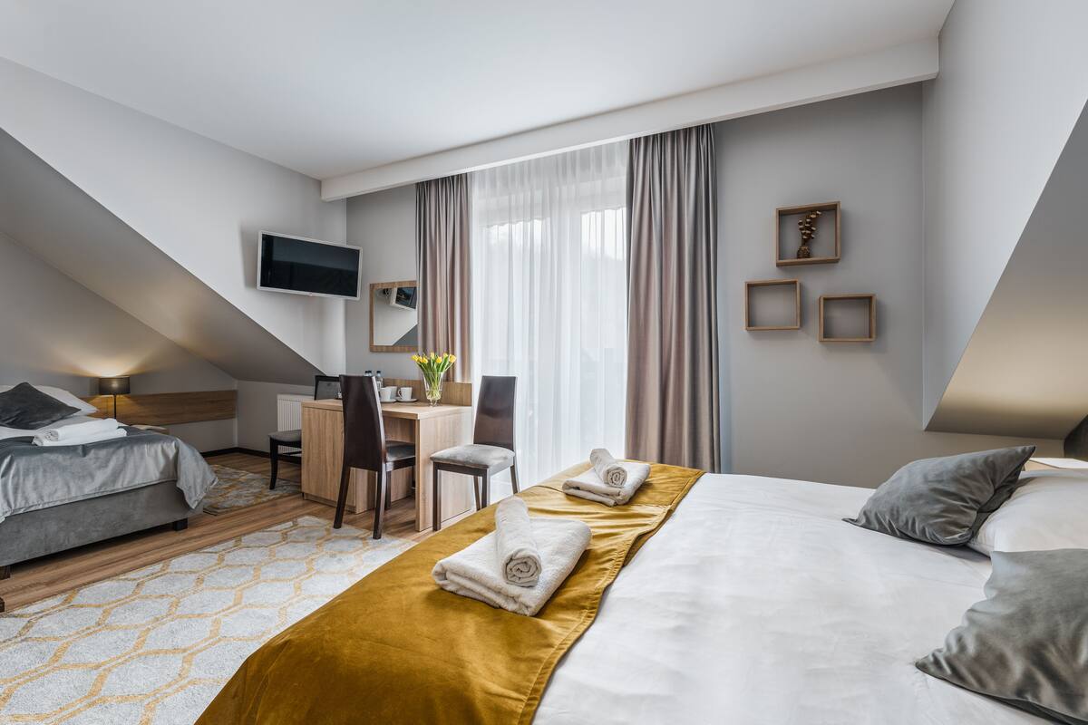 Ein modernes Hotelzimmer mit Bett, Schreibtisch und Fernseher.