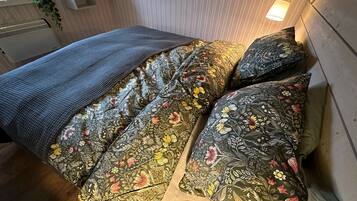 Un llit amb roba de llit de motius florals i una manta gris.