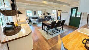 A spacious living area with a dining table, sofas, and a kitchen area with a sink and countertop. - Vindängs Gård (Sloinge)