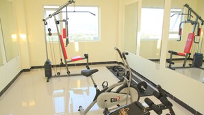 Une salle de sport équipée de matériel d’exercice, d’un banc et d’un miroir.