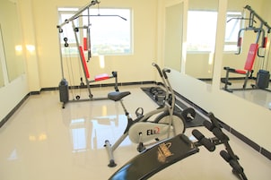 Un gimnasio con equipo de ejercicio, una banca y un espejo.