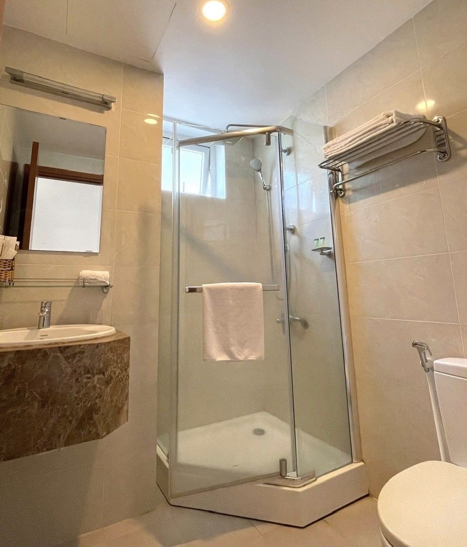 Une salle de bain moderne avec une douche à parois de verre, un lavabo en marbre et des toilettes.