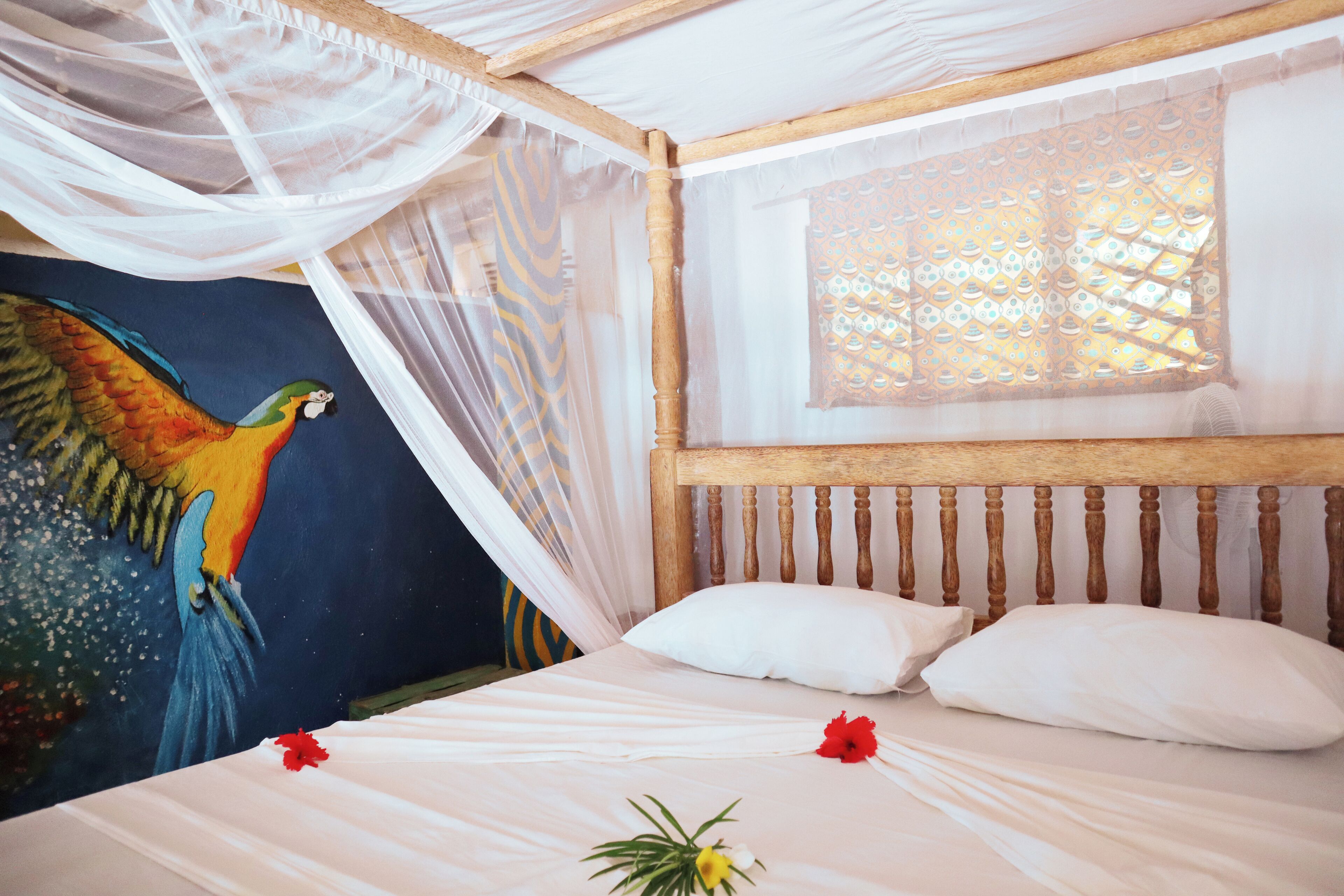 A bed with white linens, a wooden headboard, and a mosquito net.