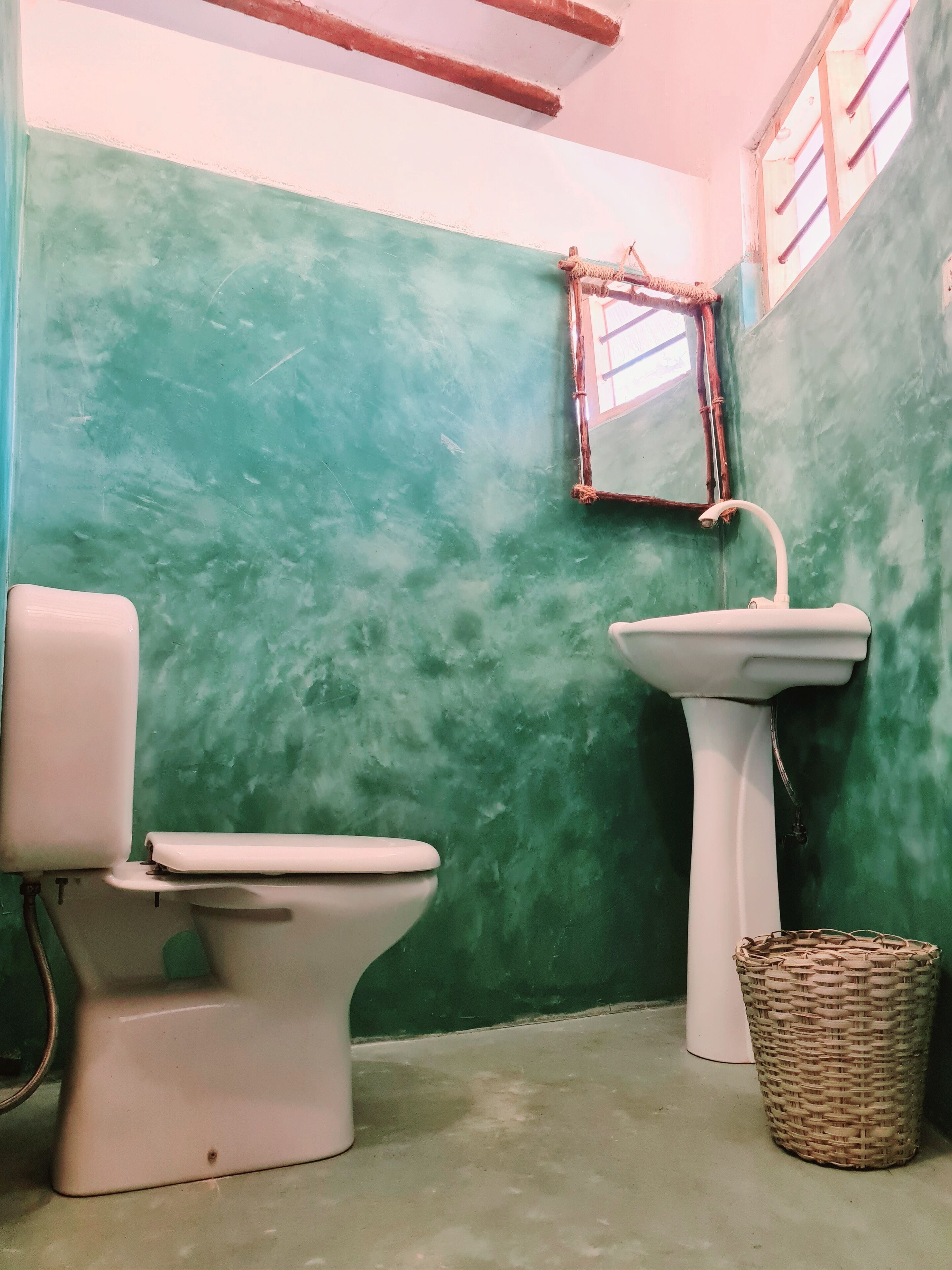 A bathroom with a green wall, a white sink, and a white toilet.