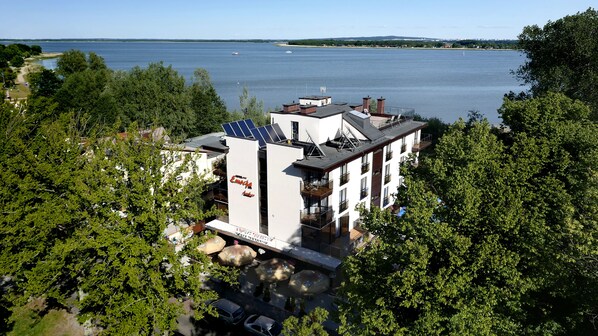 A modern hotel with a rooftop terrace, solar panels, and a view of a lake. - Hotel Emocja SPA (Mielno)