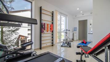 Un gimnasio con equipo de ejercicio, una cinta de correr y un perchero en la pared con toallas.