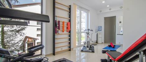 A gym with exercise equipment, a treadmill, and a wall-mounted rack with towels.